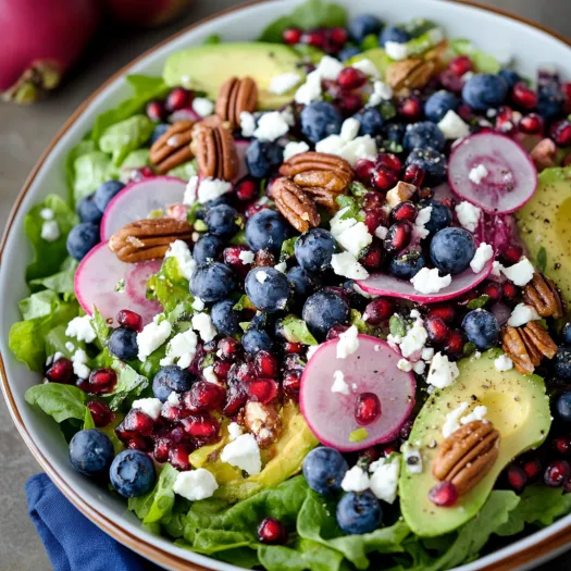 A bowl with greens, blueberries, and avocado.