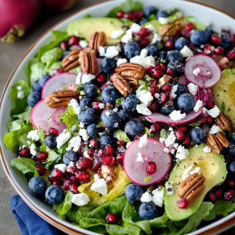 A bowl with greens, blueberries, and avocado.