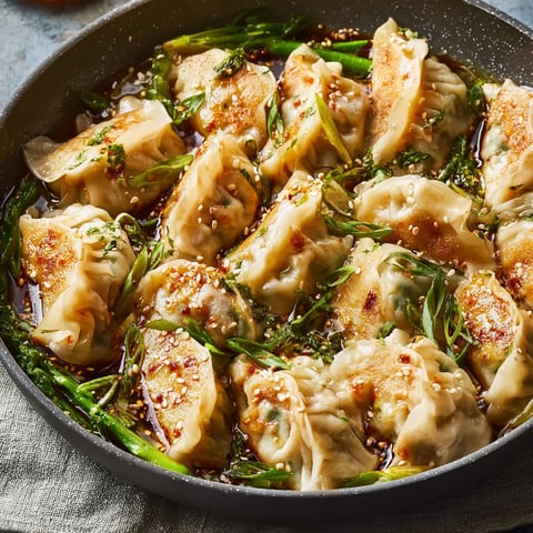 A pan of dumplings with green vegetables.