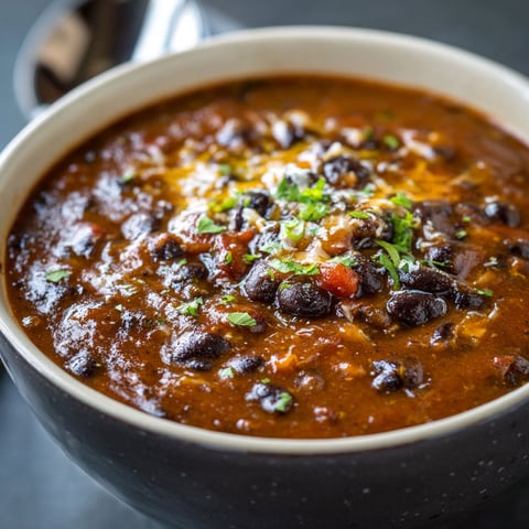 A bowl of black bean soup with a green garnish.